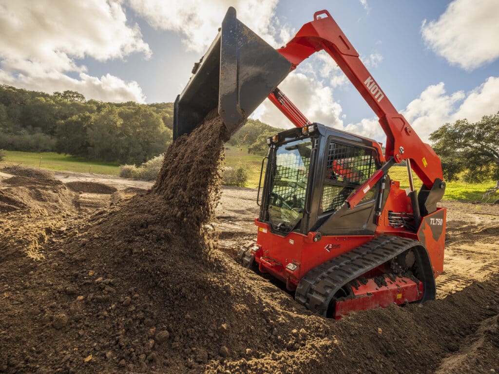 A KIOTI TL Series Skid Steer loader dumping dirt